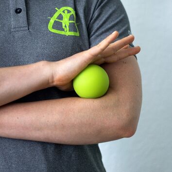 Frau rollt sich mit Faszienball die Unterarmheber aus